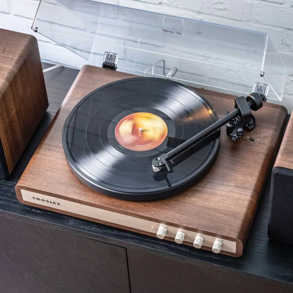 Crosley C65 Shelf System - WalnutGold showcases a spinning vinyl record on its modern walnut turntable with simple and elegant controls