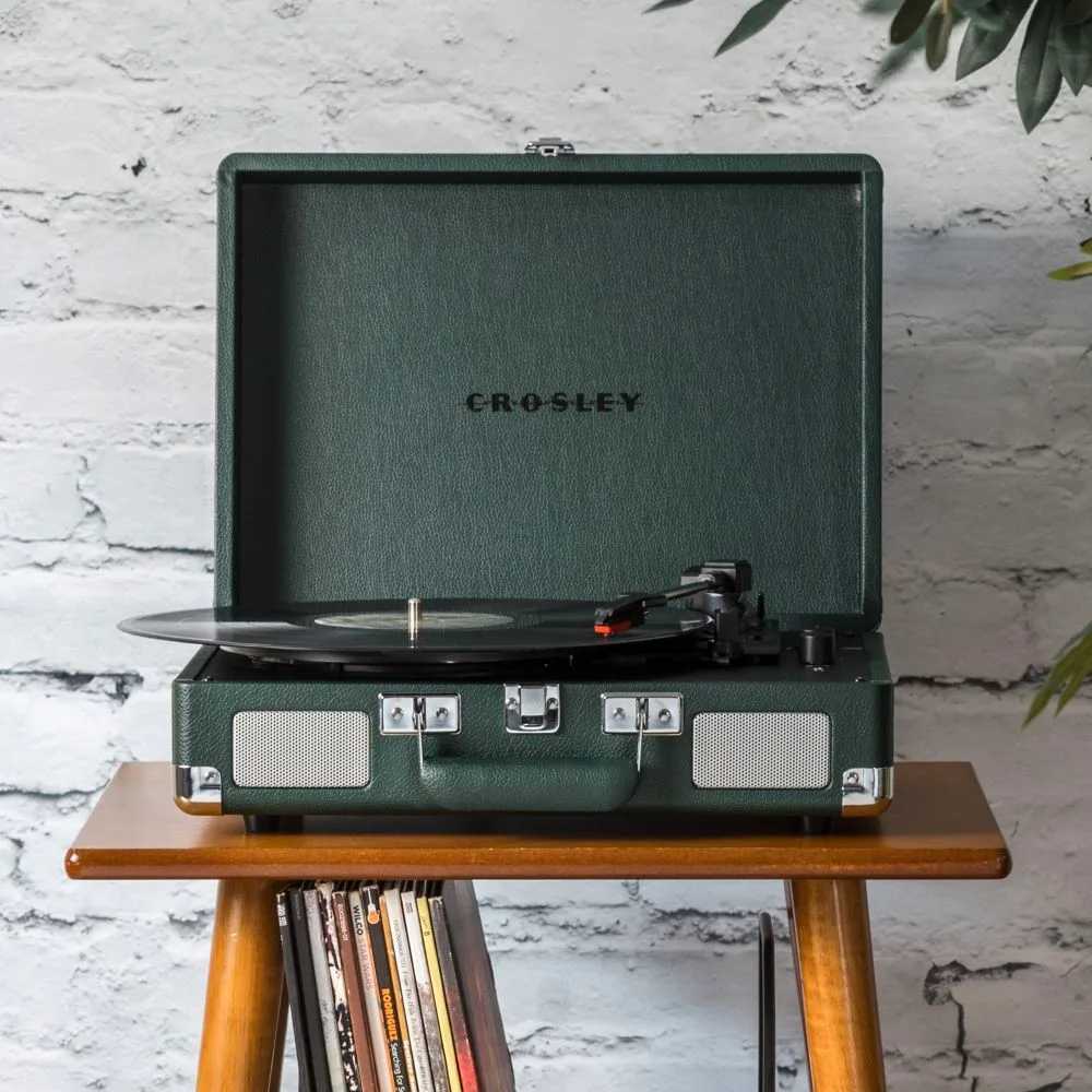 Crosley Cruiser Plus Portable Turntable with Bluetooth InOut - Emerald is displayed on a wooden stand