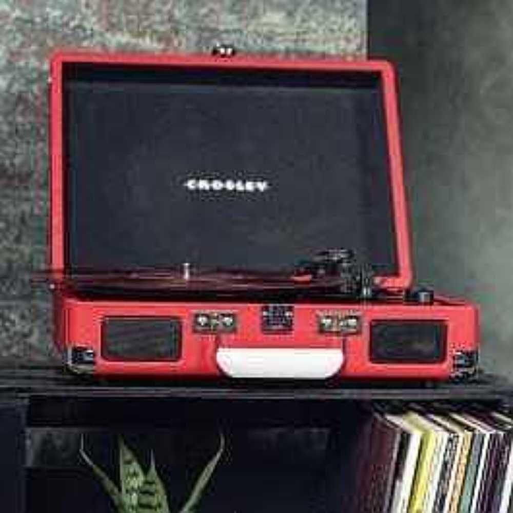 Crosley Cruiser Plus Portable Turntable with Bluetooth InOut - Exclusive Red Vinyl is shown placed stylishly on a shelf