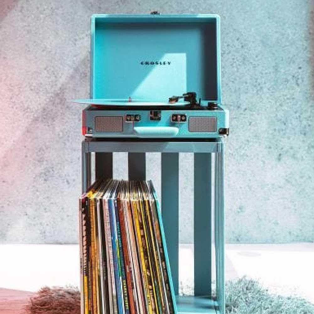 Crosley Cruiser Plus Portable Turntable with Bluetooth InOut - Exclusive Turquoise sits stylishly on a stand with vinyl records