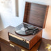 Crosley Jasper Turntable - Walnut is featured on a wooden cabinet, showcasing its compact design and functionality with a vinyl record