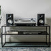 Crosley K100A Record Player with S100 Speakers - Silver is shown on a black shelf, with its turntable and speakers neatly arranged beside vinyl records