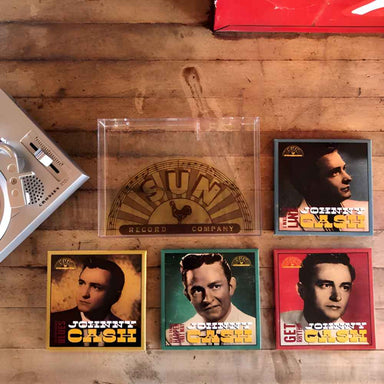 Crosley RSD3 Player + Johnny Cash 3 Inch Vinyl - Set of 4 Records is displayed on a wooden table alongside its Sun Records box and record collection