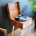 Crosley Rohe Turntable - Natural is angled to showcase its retro design and natural wood finish against a dark wall