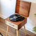 Crosley Rohe Turntable - Natural is captured mid-use with a record playing and the needle positioned on the vinyl