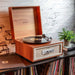 Crosley Rohe Turntable - Natural is set on a bookshelf filled with records, emphasizing its compatibility with vintage and modern interiors