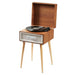 Crosley Rohe Turntable - Natural is shown in a full view with its wooden lid open, playing a vinyl record on its legs