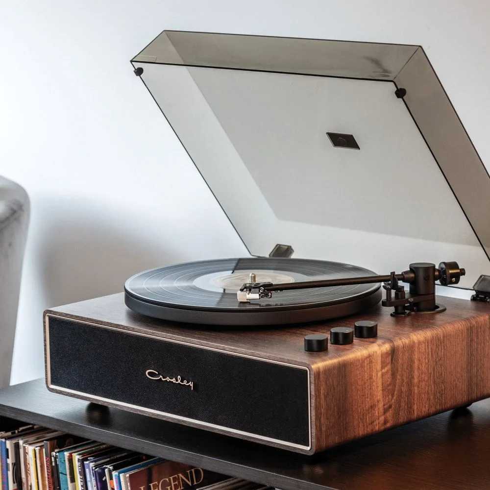 Crosley Stave Record Player - WalnutGold is shown playing a vinyl record with its sleek walnut wood design and gold accents