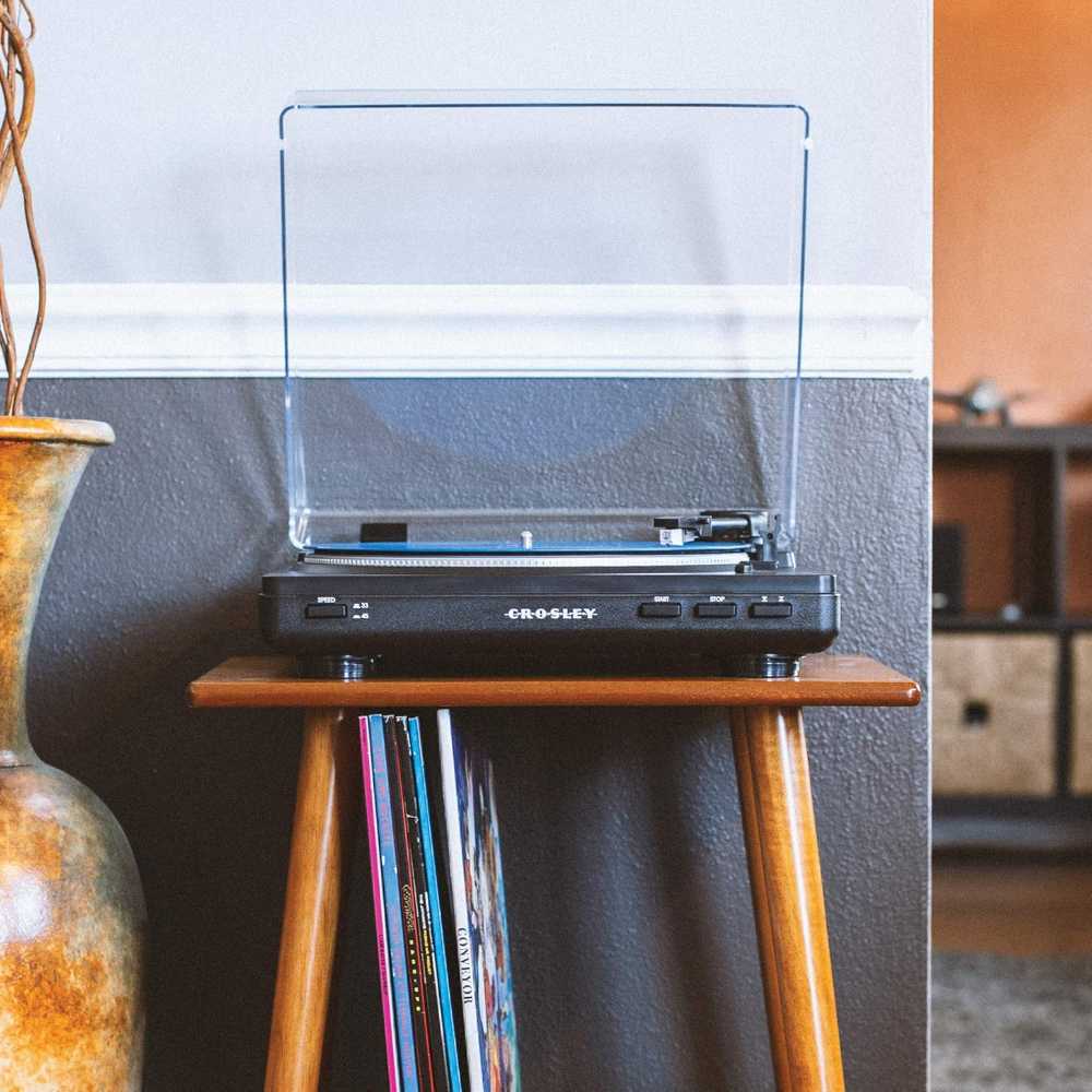 Crosley T400D Component Bluetooth Turntable - Black sits on a wooden table with vinyl records stored below