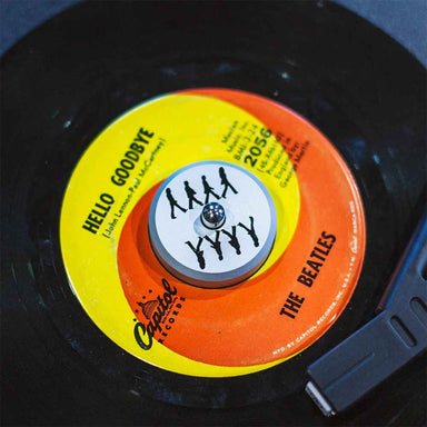 Crosley The BEATLES 45 Adapter - Abbey Road Mirror in use on a vinyl record, displaying its design with The Beatles’ silhouettes over the center of a record labeled Hello Goodbye.