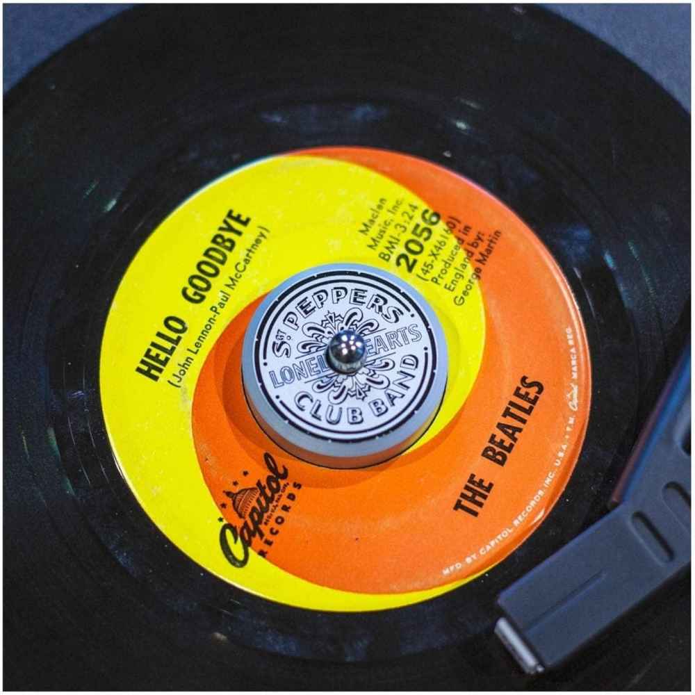 Crosley The BEATLES 45 Adapter - Sgt. Pepper attached to a Beatles vinyl record labeled Hello Goodbye on a turntable