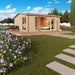 Set in a landscaped garden with flowers and a blue sky, the GardenHouse24 USA Davos 44B Garden Room features large glass doors and deck chairs outside