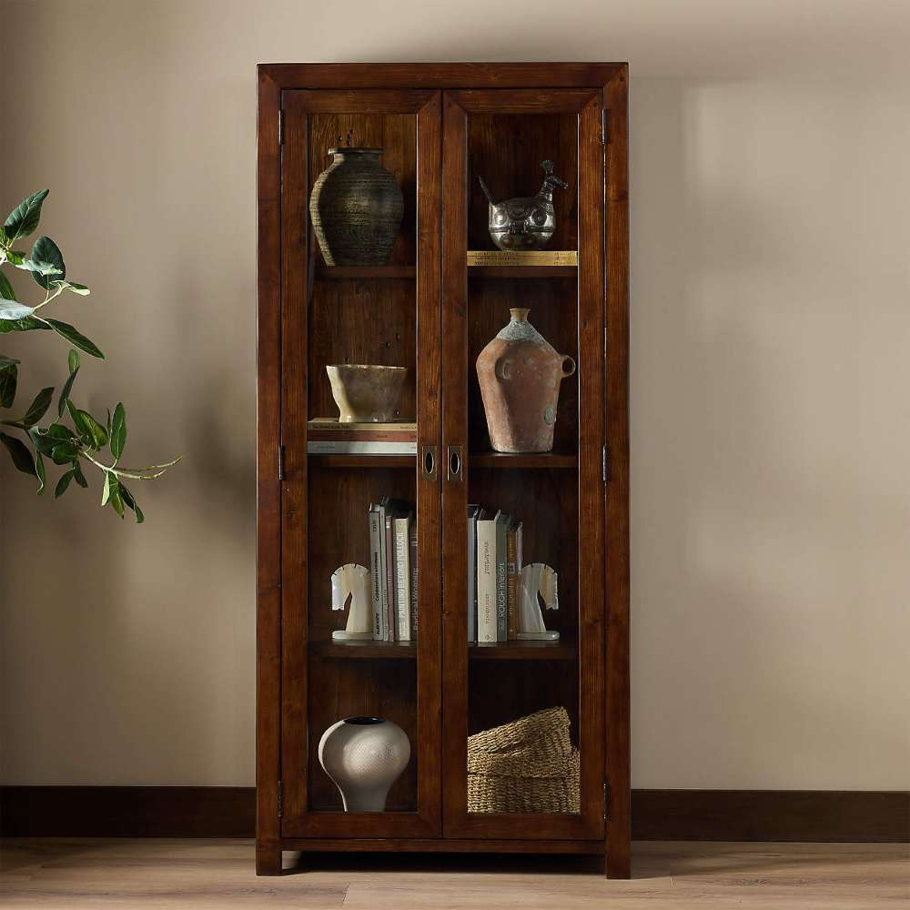 Decorative display inside Crate & Barrel Morris 36" Chocolate Brown Wood and Glass Bookcase Cabinet with books and pottery