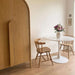 Dining room featuring Crate & Barrel Annie 38" Natural Storage Cabinet beside a round table and wooden chairs