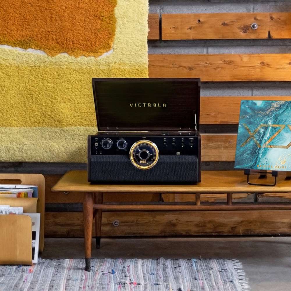Displayed in a colorful room, the Victrola Empire Bluetooth Record Player sits on a wooden console
