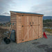 Double Door Metal Roof Outdoor Living Today 8×4 SpaceSaver Lean-To Cedar Shed stands on gravel with yard tools