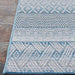 Edge of the Couristan Cape Indoor/Outdoor Rug - Gables/Surf is shown resting on a stone floor