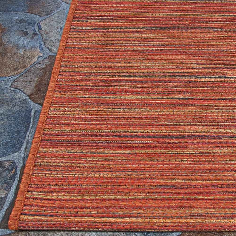 Edge of the Couristan Cape Indoor/Outdoor Rug - Hinsdale/Crimson-Multi is pictured on a stone patio, showing its bright red-orange border and horizontal lines