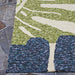 Edge of the Couristan Covington Indoor/Outdoor Rug - Monstera/Cream-Multi is shown lying flat on a slate patio, highlighting its clean finish