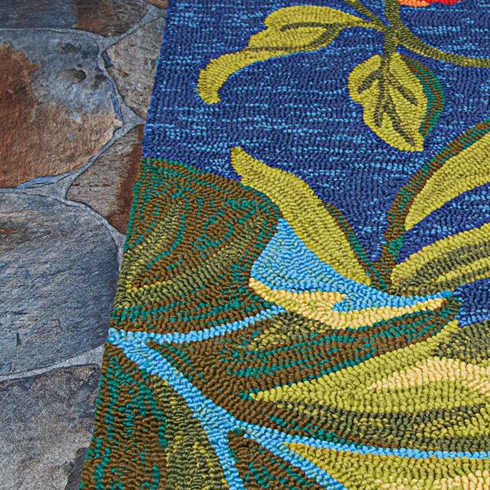 Edge of the Couristan Covington Indoor/Outdoor Rug - Tropical Orchid/Azure-Forest Green-Red rests on stone flooring