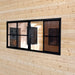 Straight interior view of a large black-framed Eze-Breeze sliding-window system installed in a pale pine wall, showing multiple sliding panels and an adjoining wooden room.