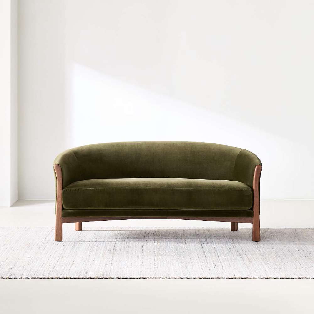 Fabric Olive (Como Velvet) Crate & Barrel Contour Sofa displayed on a light area rug, showcasing its curved silhouette and olive velvet upholstery in a minimalist room