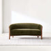 Fabric Olive (Como Velvet) Crate & Barrel Contour Sofa displayed on a light area rug, showcasing its curved silhouette and olive velvet upholstery in a minimalist room