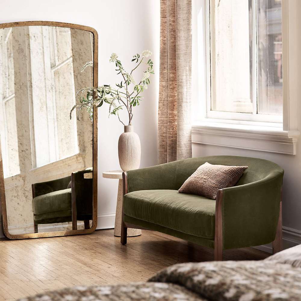 Fabric Olive (Como Velvet) Crate & Barrel Contour Sofa in olive green velvet sits beside a large floor mirror and a small side table in a bright, cozy room