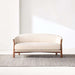 Fabric Tapioca (Lucie Boucle) Crate & Barrel Contour Sofa displayed on a textured rug, showcasing its curved silhouette and cream boucle upholstery