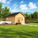 Farum 44 wooden garden room with a dark gabled roof and warmly lit glazed doors, set in a fenced backyard with patio seating, flower planters and mountain views.