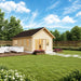 Small light wood cabin with a dark gabled roof, glass double doors, and a patio with white seating on a green lawn.