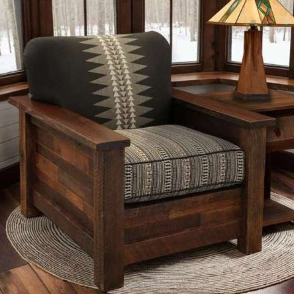 Fireside Lodge Barnwood Americana Lounge Chair is pictured in a cozy cabin-style room, showcasing its rustic wood frame and patterned cushions beside a craftsman-style lamp