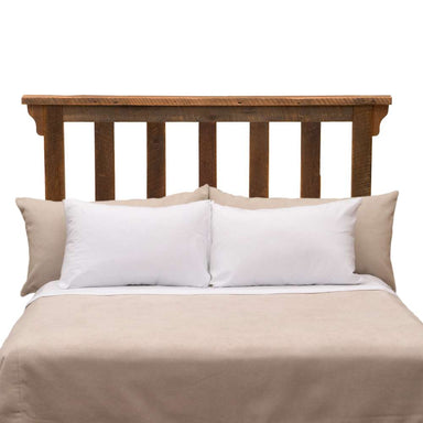 Fireside Lodge Barnwood Post Headboard stands behind a bed with vertical wooden slats and a warm, weathered brown finish