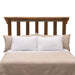 Fireside Lodge Barnwood Post Headboard stands behind a bed with vertical wooden slats and a warm, weathered brown finish