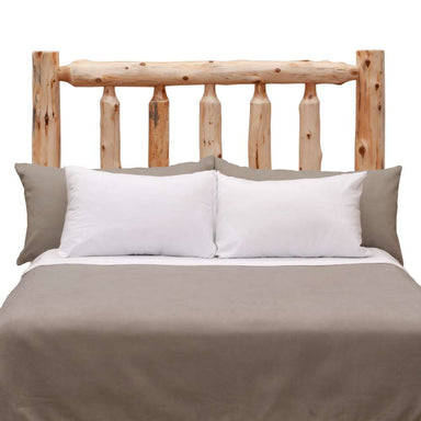 Fireside Lodge Cedar Log Traditional Headboard displayed behind a made bed, featuring natural cedar logs with a sturdy, handcrafted rustic design