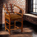 Fireside Lodge Hickory Log Hoop Counter Stool with Back is a rustic hickory log stool with a leather seat and Southwestern-patterned back, set in a cozy brick room