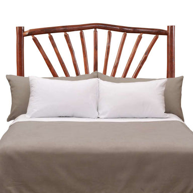 Fireside Lodge Hickory Log Sunburst Headboard is shown on a bed with its rustic sunburst log design visible above the pillows