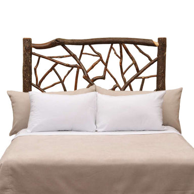 Fireside Lodge Hickory Log Twig Headboard features a rustic log frame with intertwined twig details behind a bed with light neutral bedding