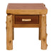 Fireside Lodge One Drawer End Table is a rustic wooden table featuring a thick, natural wood slab top, sturdy log legs, and a single drawer with a handcrafted log pull