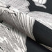Folded portion of Couristan Dolce Indoor/Outdoor Rug - Flora/Nero highlights the thick woven texture and intricate cream flower detailing on the black surface