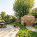 Font yard view with a path leading to the 8x8 Outdoor Living Today Western Red Cedar Greenhouse Kit in a landscaped garden