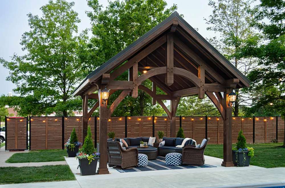 Front view of Brookside Timber Frame Alpine Lodge Pavilion showcases its intricate wooden structure and lantern-style lighting
