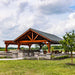 Front view of Brookside Timber Frame Combolan Estate Pavilion showcases its high-quality timber construction, a stylish metal roof, and an inviting outdoor kitchen setup