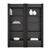 Front view of Crate & Barrel Siena 68" Black Wood 4-Shelf Storage Bookcase with Drawer, Set of 2 styled with books vases and decorative accents