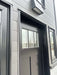 Front door of Sawmill Structures Wanderlove Tiny Home is framed by dark siding and topped with a rectangular black exterior light