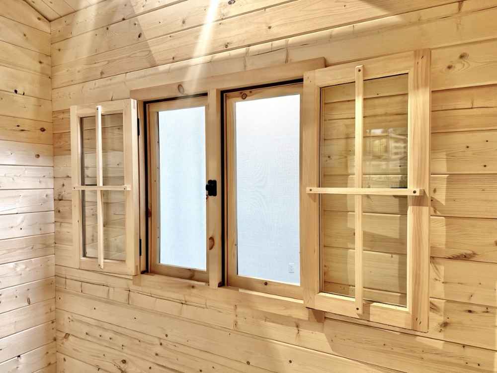 Frosted glass windows with open wooden shutters illuminate the room inside the Sawmill Structures Ontario Grand Loft 107 SD Garden Room