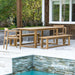 Full outdoor patio setup shows Westminster Teak Horizon Table & Bench Set with benches and chairs placed beside a pool and greenery
