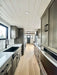 Galley-style kitchen in Sawmill Structures Wanderlove Tiny Home runs the length of the home with cabinetry, counters, and appliances