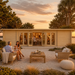 Front view of the Game Room 70 transformed into an upscale golden-hour backyard bar, with friends gathering in a coastal Florida garden beside a calm inlet.