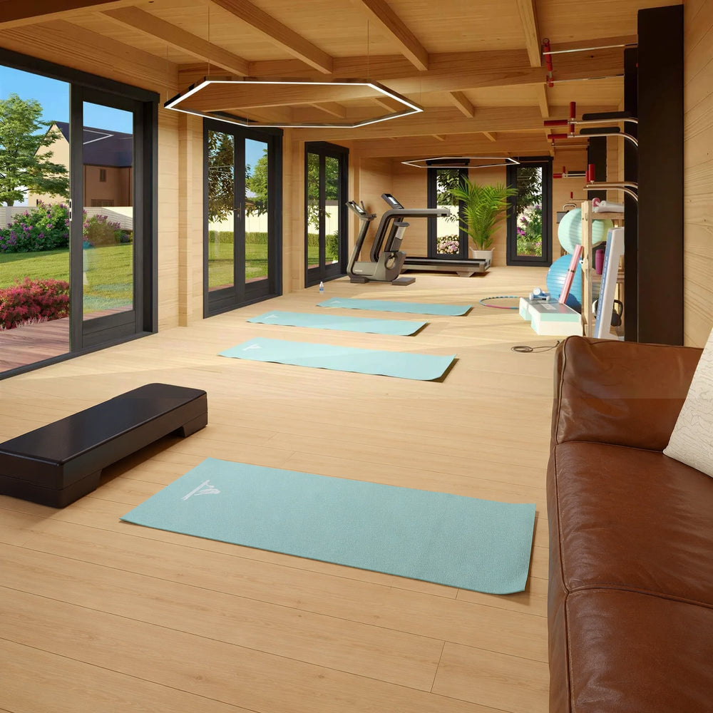 Inside the GardenHouse24 USA Game Room 70 Garden Room, a spacious workout area is equipped with treadmills, yoga mats, gym gear, and large windows offering a scenic garden view